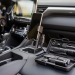 Comment bien choisir ses accessoires auto pour un usage quotidien Intérieur de voiture moderne avec accessoires bien rangés sur la console centrale : support pour téléphone, chargeur USB et kit de sécurité clairement visible.